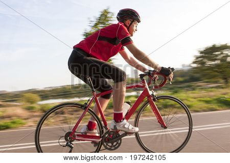 Sport and Cycling Concepts and Ideas. Professional Male Cyclist During a Ride on Bike Outdoors. Panning Technique. Horizontal Image Composition