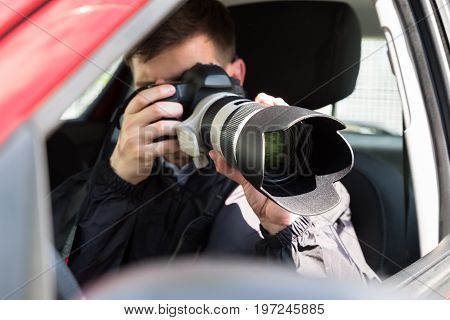 Side View Of A Private Detective Sitting Inside Car Photographing With Slr Camera