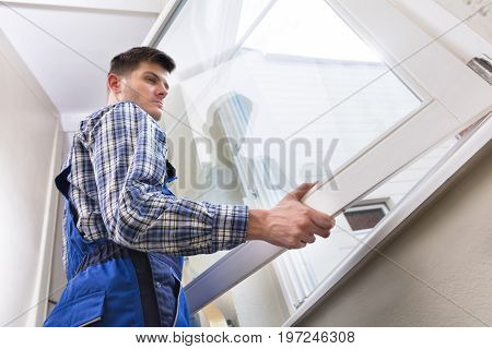 Low Angle View Of A Young Male Repairman Installing Window