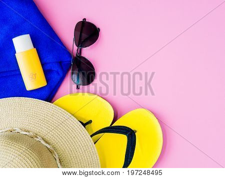 Sunglasses with summer hat sunscreen lotion blue towl and flip flops on pink background.Vacation and relaxation summer travel concept.