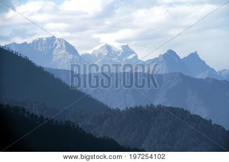 Morning mountain landscape with layer of mountain peaks covered with coniferous deciduous forests. View from Dochula Pass on the road from Thimphu to Punaka Bhutan