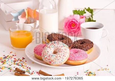 American donuts with rainbow sprinkles on white dish.
