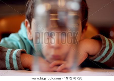 A young child behind a glass of water