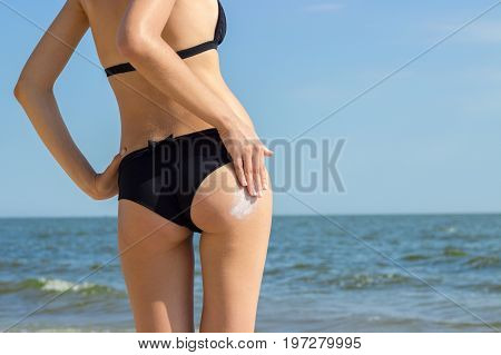 Suntan Lotion Woman Applying Sunscreen Solar Cream. Beautiful cute girl applying Sun Tan Cream on her skin on the beach. Sun Tanning. Skin care and Protection. Vacation