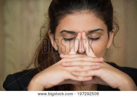 Close-up of face of tired young Caucasian woman rubbing nose. Businesswoman suffering stress or depression