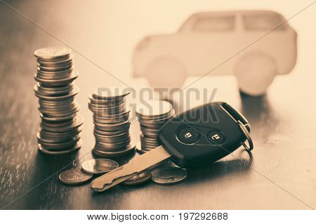 key of car and staced of money coins on wood table