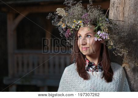 Portrait of a romantic smiling woman in a circlet of flowers outdoors.