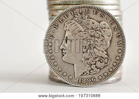 1896 Morgan Dollar coin stands against a stack of coins.