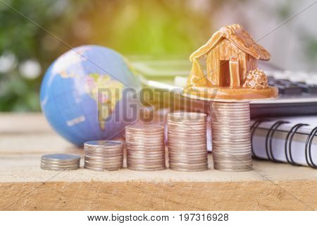 pile of coinsglobe and home concept in house finance on wood table
