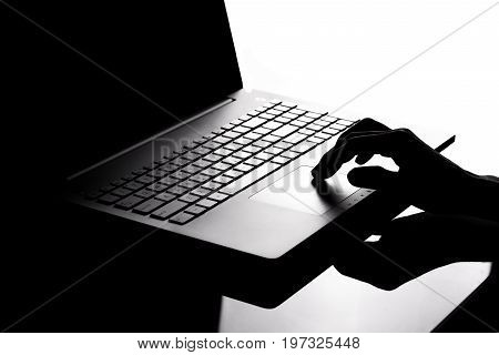 a conceptual phone of hacker hand clicking on a mouse pad of a laptop in white and black