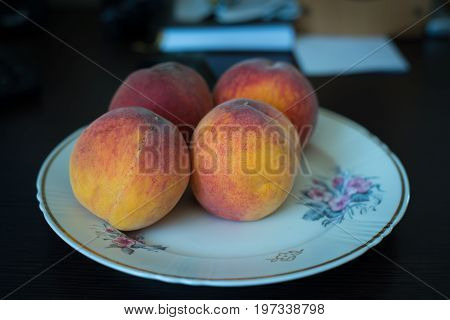 A four nice orange peaches on a plate