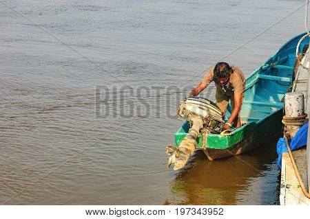 Goa, India - November 13, 2012: Lifestyle in Chorao island, Goa, India. Old boat for transportation to the Salim Ali Bird Sanctuary and its boatman starts the motor.