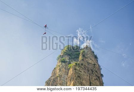 Aerial performers on high wire in the DaLong waterfall scenic area within Yandangshan near Yandang Town Yueqing County Zhejiang province China.