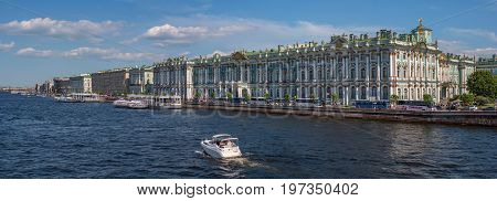 Hermitage palace on the bank of Neva river. The waterfront is moored excursion boats. On the waterfront there are many tour buses. Saint Petersburg, Russia.