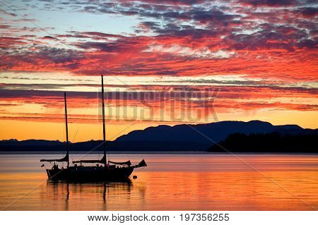 Silhouetted sailboat at sunset on the west coast of British Columbia, Canada