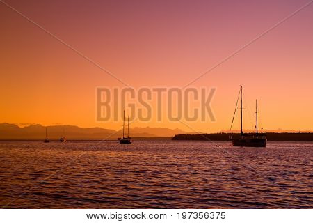 Silhouetted sailboats at sunset on the west coast of British Columbia, Canada