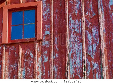 Weathered barn wood has a window in it.