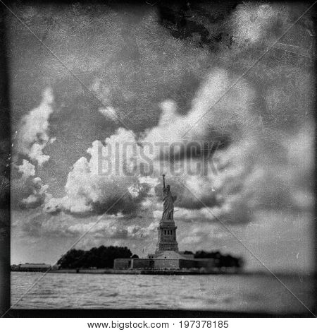 Vintage filter effect of the Statue of Liberty and clouds in New York Harbor on the East River. TinType / Wet plate effect. Black and White. 