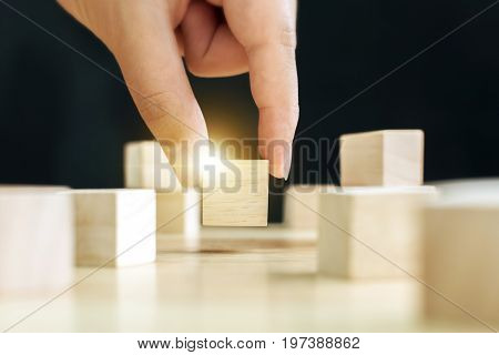 Hand of male pick up on one wooden block from many Business ideas for choosing something that looks distinctive concept
