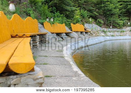 Original wooden benches on shore of lake in Ukrainian Carpathians