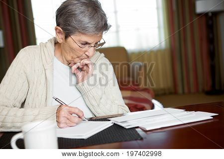 Senior Woman Paying Bills At Home In Her Office