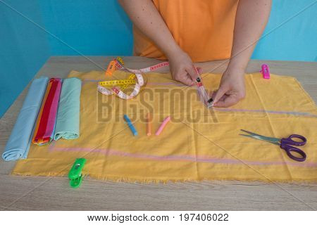 woman hands sewing yellow cloth outdoors. Tailor hands working with scissor and suit textile cloth