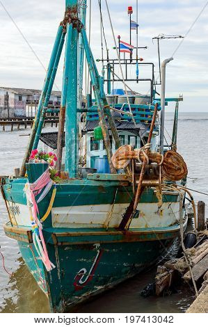 A wooden fishing boat moored to a pier in to the village in Thailnd province Khlong Yai