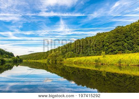 Evening photo of the river. The river runs among woods.
