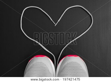 Fitness concept. Love to sport. Sneakers (sport shoes) with shoelaces as form of heart on black background.