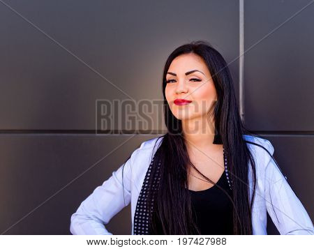 Portrait of a beautiful brunette that stands near a black wall. Close-up.