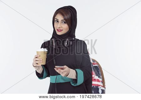 arab student wearing hijab holding mobile and coffee cup