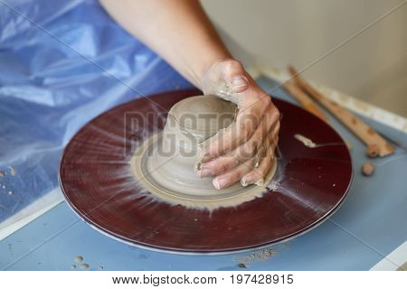 Creating a jar or vase of clay. Woman hands on potter's wheel