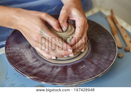 Creating a jar or vase of clay. Woman hands on potter's wheel