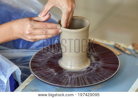 Creating a jar or vase of clay. Woman hands on potter's wheel