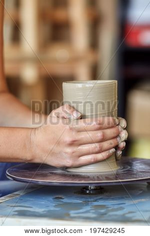 Creating a jar or vase of clay. Woman hands on potter's wheel