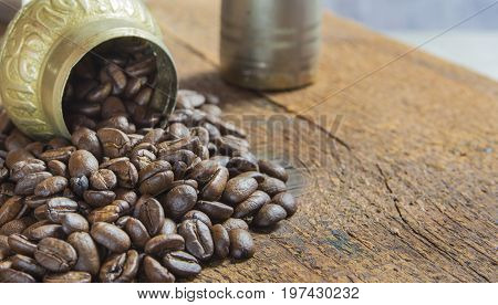 Roasted coffee beans on the wood with small coffee grinder