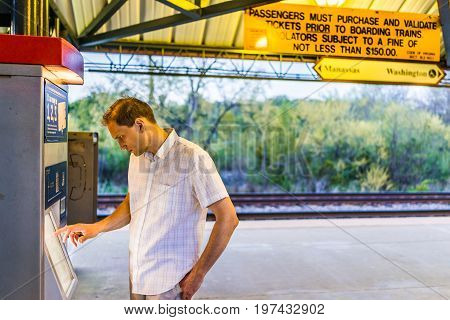 Burke, Usa - April 16, 2017: Young Man Buying Tickets In Machine At Burke Centre Train Station Platf