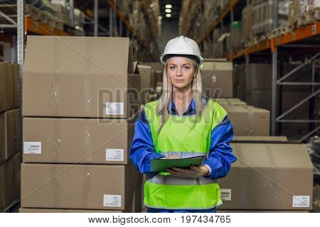 Female warehouse worker looking at camera in logistic center