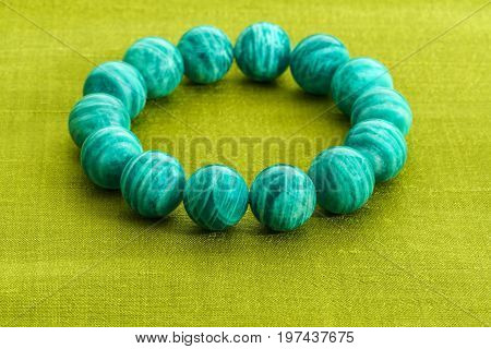 Beautiful Amazonite or Amazon stone beads in bracelet on green Thai silk background