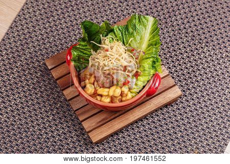 Fresh salad with lupini beans and raw fish served with lettuce leaf in bowl on table napkin