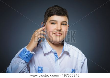 Closeup Portrait of happy boy with mobile or cell phone on gray background.