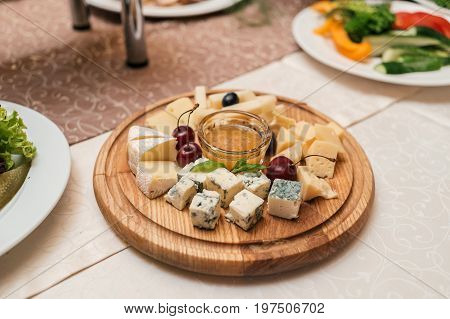 Cheese Plate With Cherries And Honey On Round Wooden Board Plate On Celebratory Dinner Table, Select
