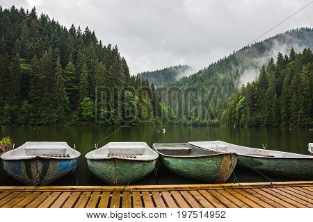 Mountain lake scenery Lacu Rosu or Red lake with boats near the shore Eastern Carpathians Romania nature landscape background.