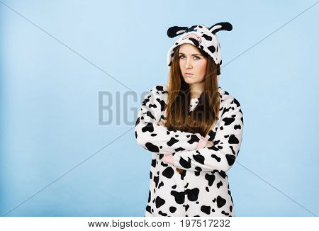 Teen girl in funny nightclothes pajamas cartoon style showing angry offended face expression studio shot on blue. Negative emotion concept.