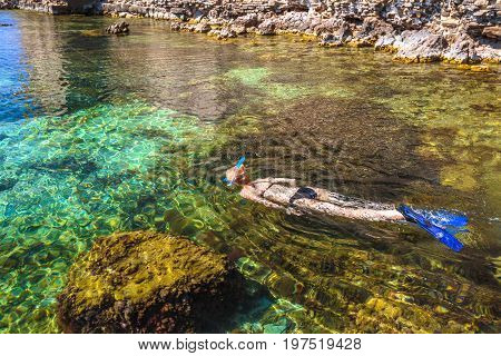 Watersport leisure activity. Snorkeling in Greece by Methoni Castle in Methoni, Messenia, Peloponnese, Greece. Young female in bikini snorkeling in beautiful clear waters. Summer holidays concept.