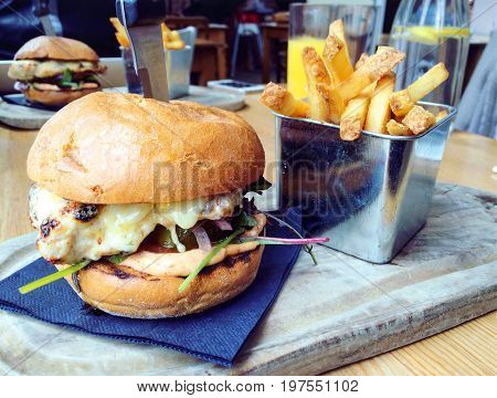 A juicy chicken burger with a knife in it served with chips