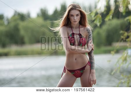 Sexy tattooed woman in lingerie in a river water.Sexy young woman relaxing on the beach.