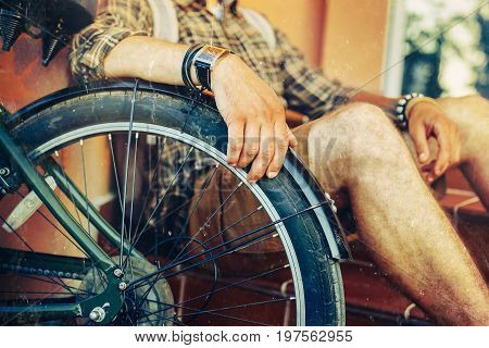 Closeup young guy hand lies on a bicycle wheel