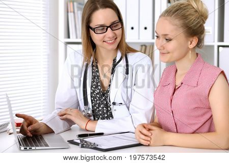 Doctor discussing confidental medical history with his patient and pointing at monitor computer.