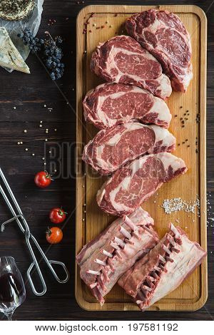 Fresh Raw Beef steak with salt, peppercorns and tomatoes on the wood board